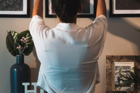 Immagine di una donna di spalle che sta sistemando un dipinto